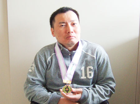 誇らしげにメダルをかざされる藤田さん(ブルースカイ)